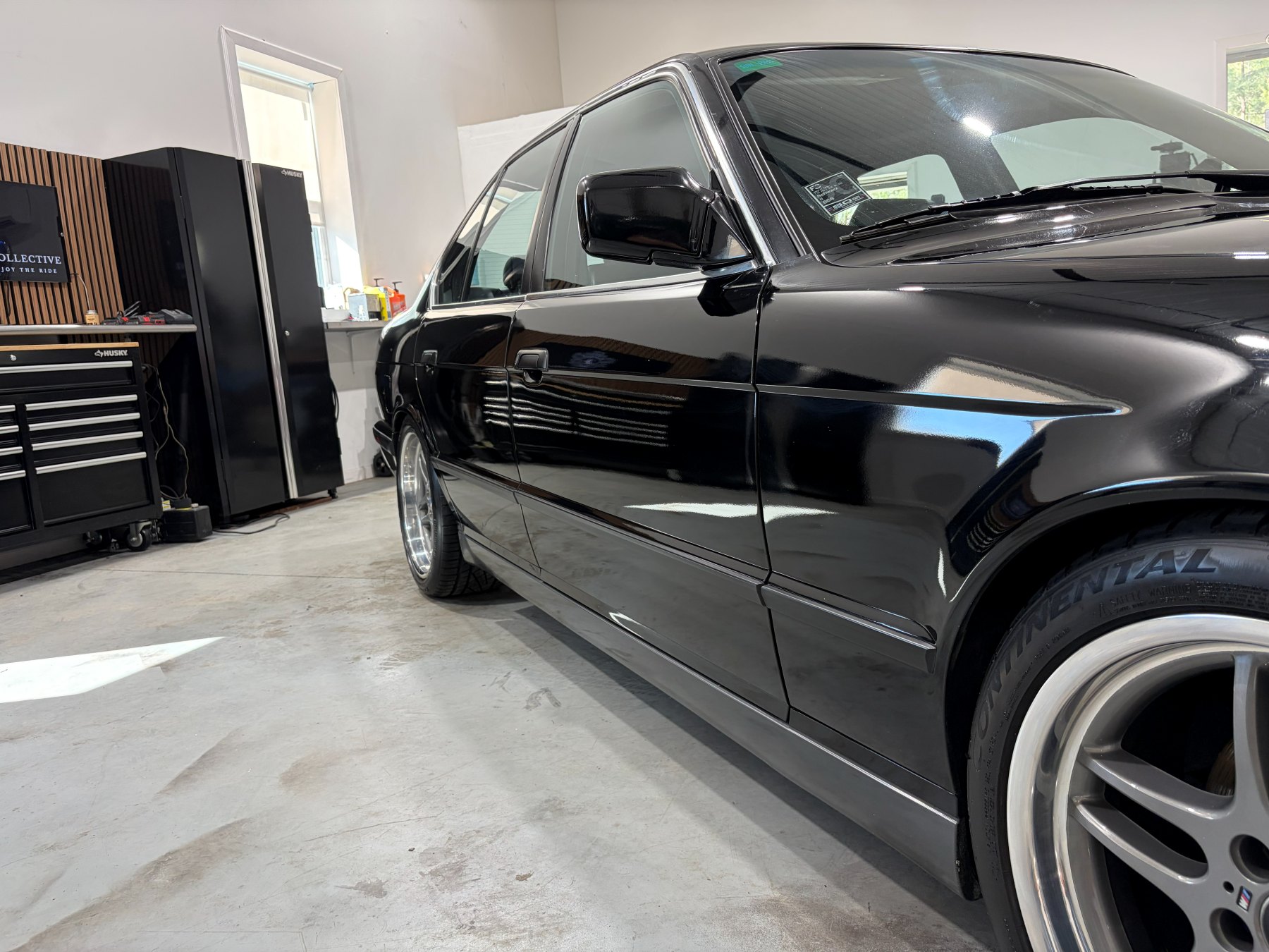 Black BMW M5 driver-side reflection after paint polishing