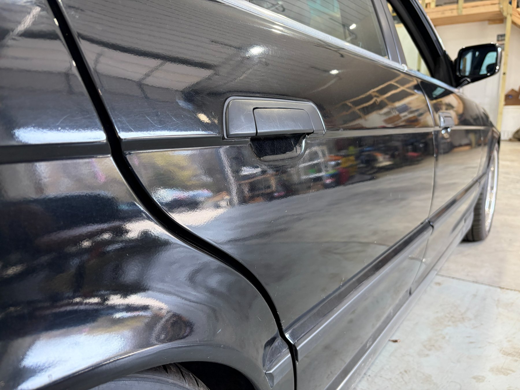 Black BMW M5 driver-side reflection before paint polishing