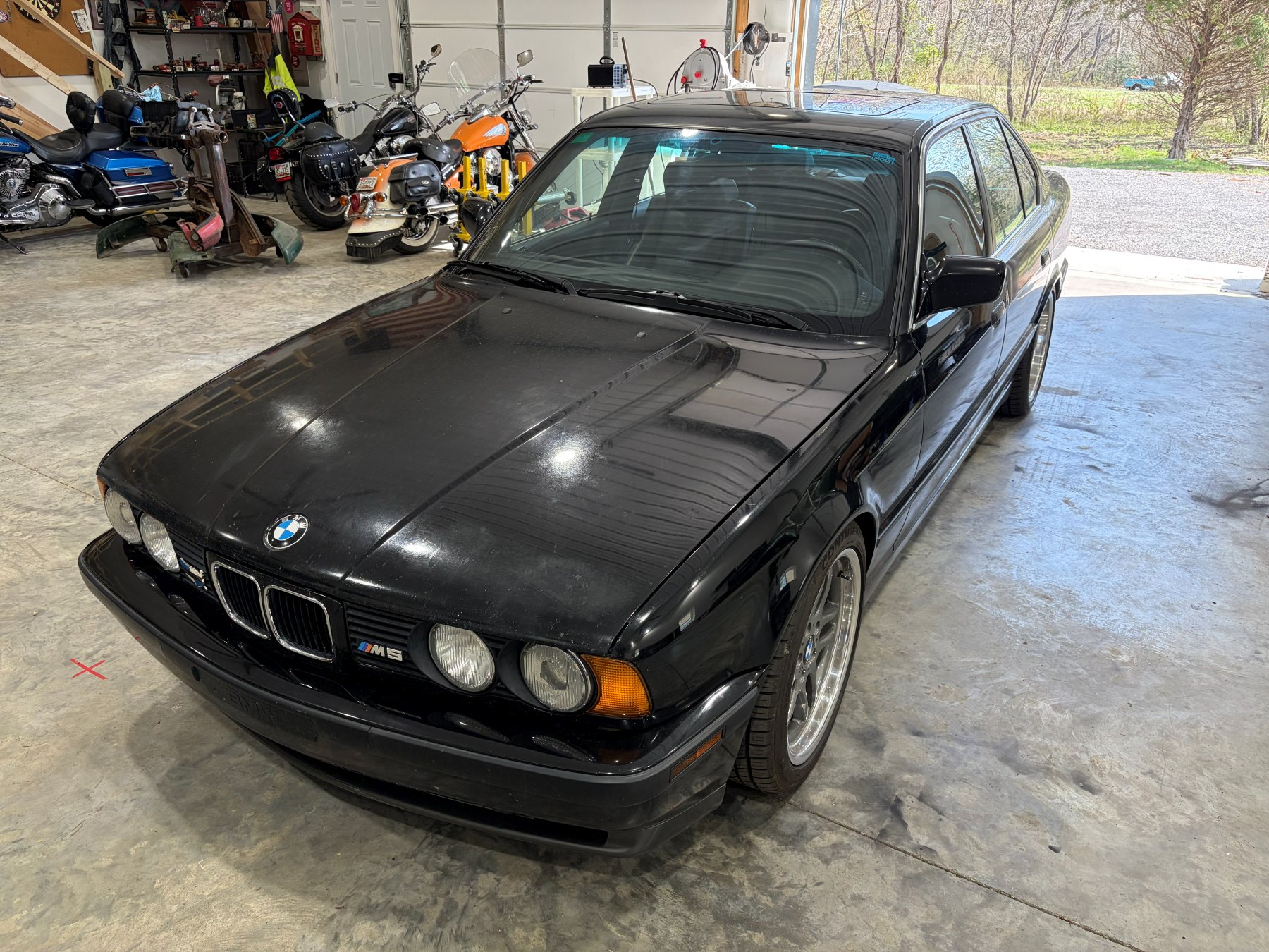 Black BMW M5 before paint polishing from the front left angle