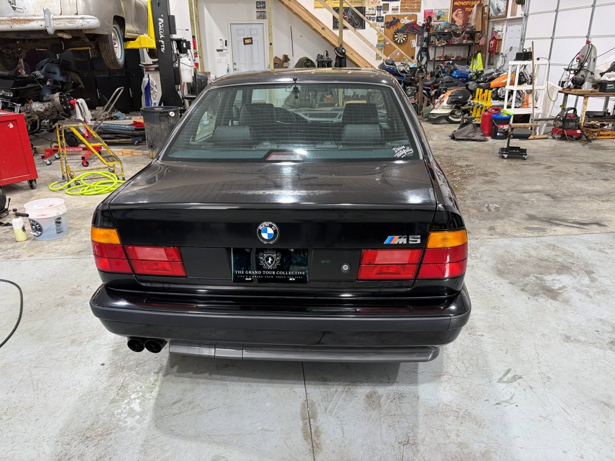 Black BMW M5 rear view before paint polishing