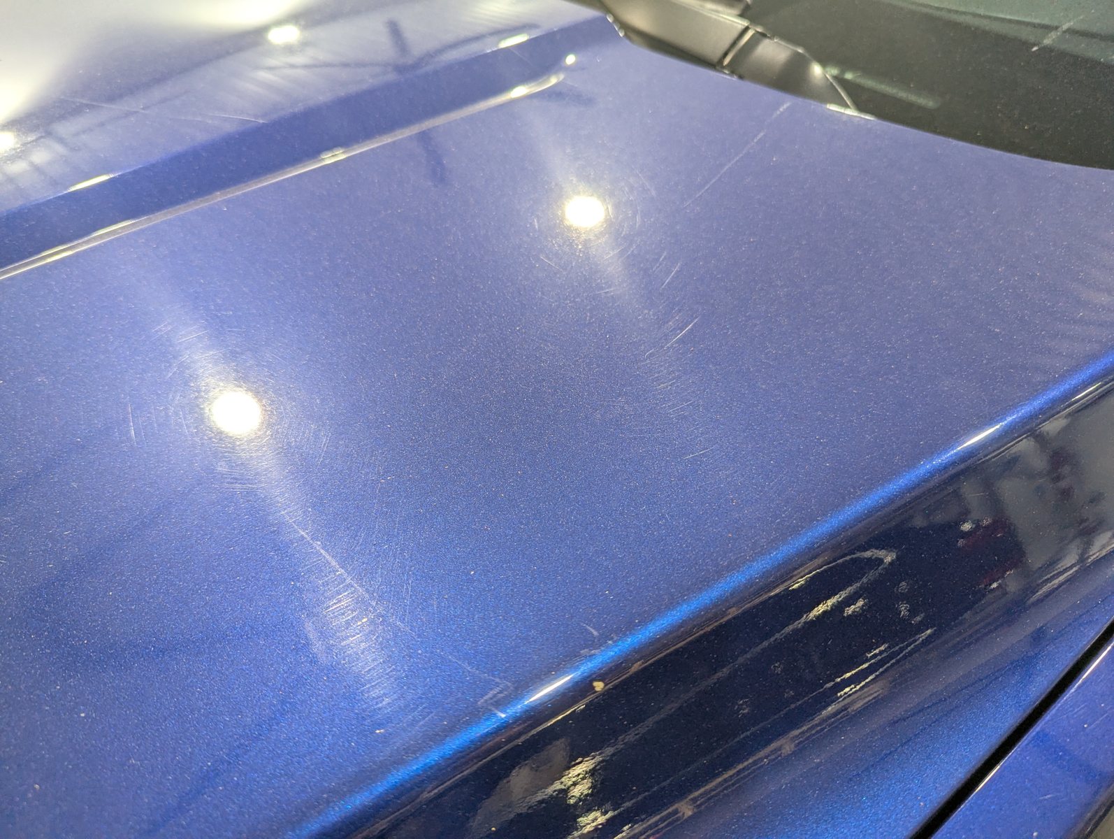 Before paint polishing on a blue Cadillac ATS hood with visible haze and swirl marks
