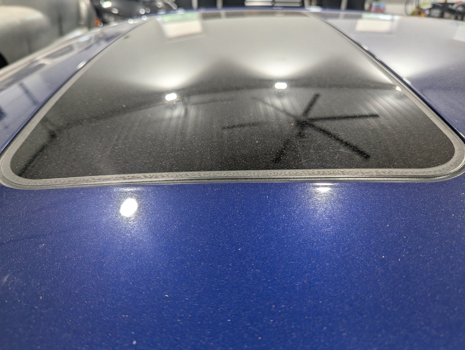 Before paint polishing on a blue Cadillac ATS roof with visible swirl marks